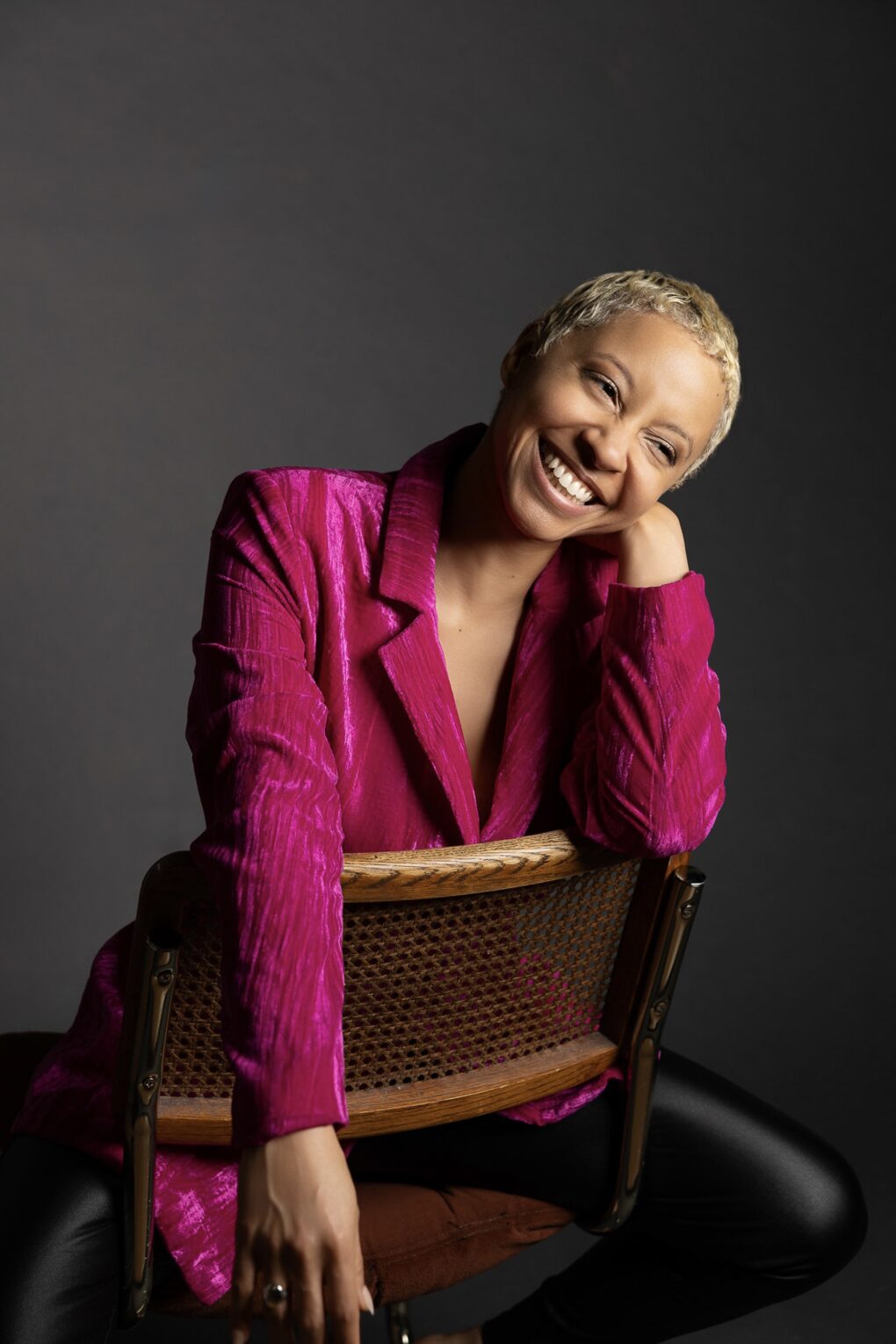woman sitting in a chair with a pink blazer and black pants
