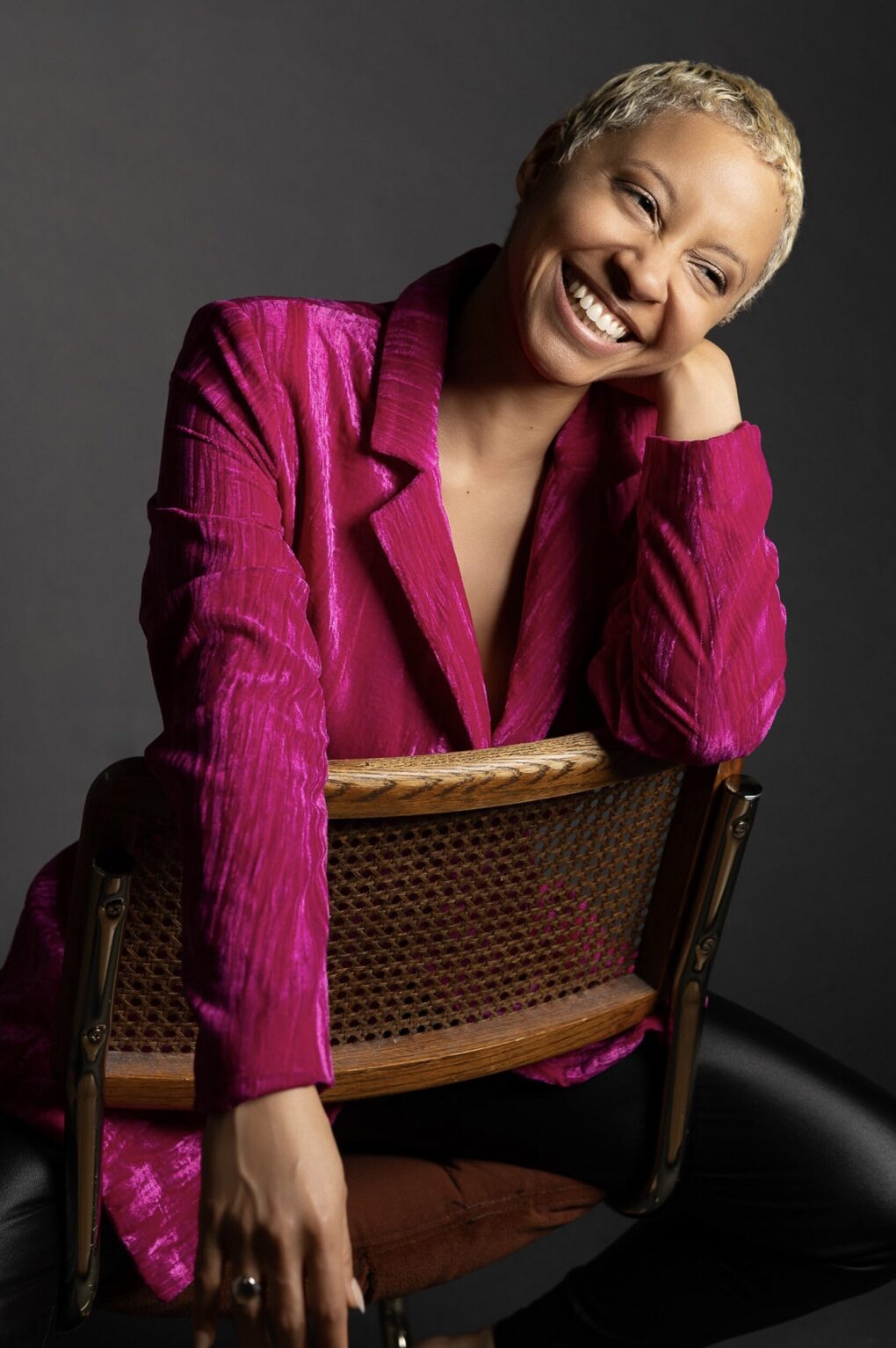 woman sitting in a chair with a pink blazer and black pants